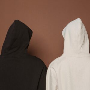 Home Back view of two hoodies in white and black against a brown background.